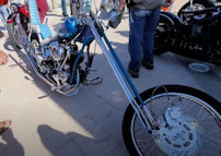 A custom chopper on display at a motorcycle show, surrounded by admiring onlookers, symbolizing the shift from garage to gallery.